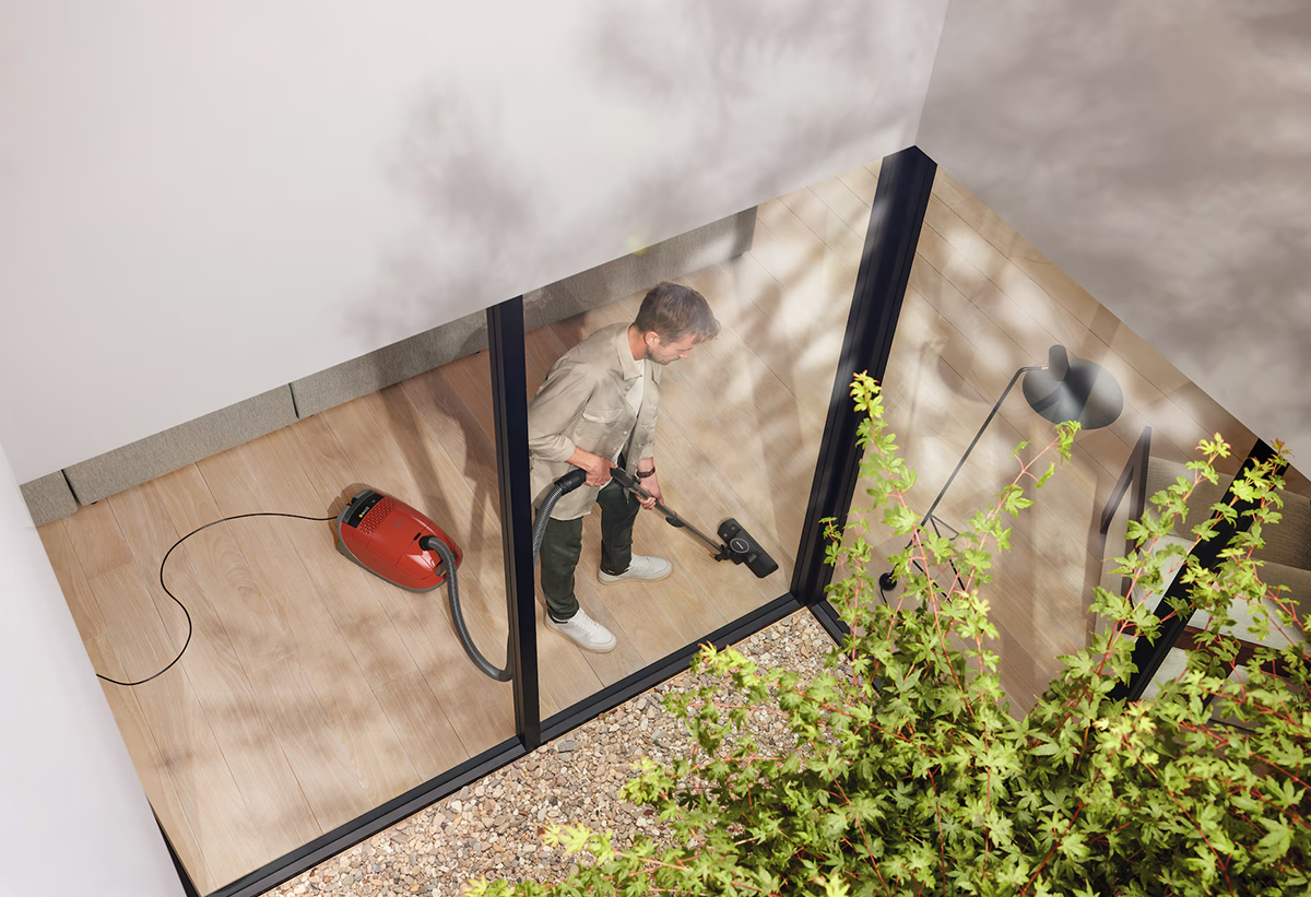 Ένας άντρας καθαρίζει το πάτωμα του σπιτιού του με τη σκούπα.